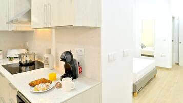 A modern kitchen with a coffee machine, a plate of croissants, and a glass of orange juice.