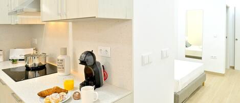A modern kitchen with a coffee machine, a plate of croissants, and a glass of orange juice.