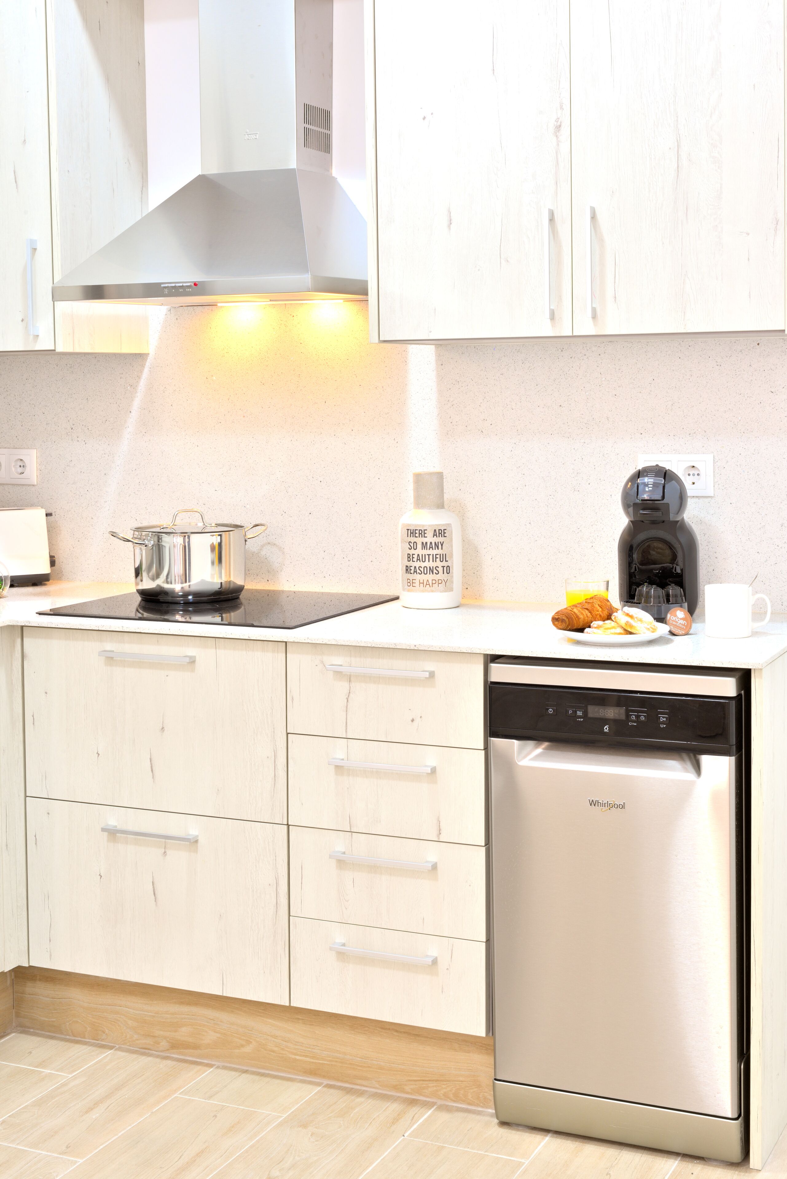 Een moderne keuken met een inbouwfornuis, een koffiezetapparaat en een vaatwasser.