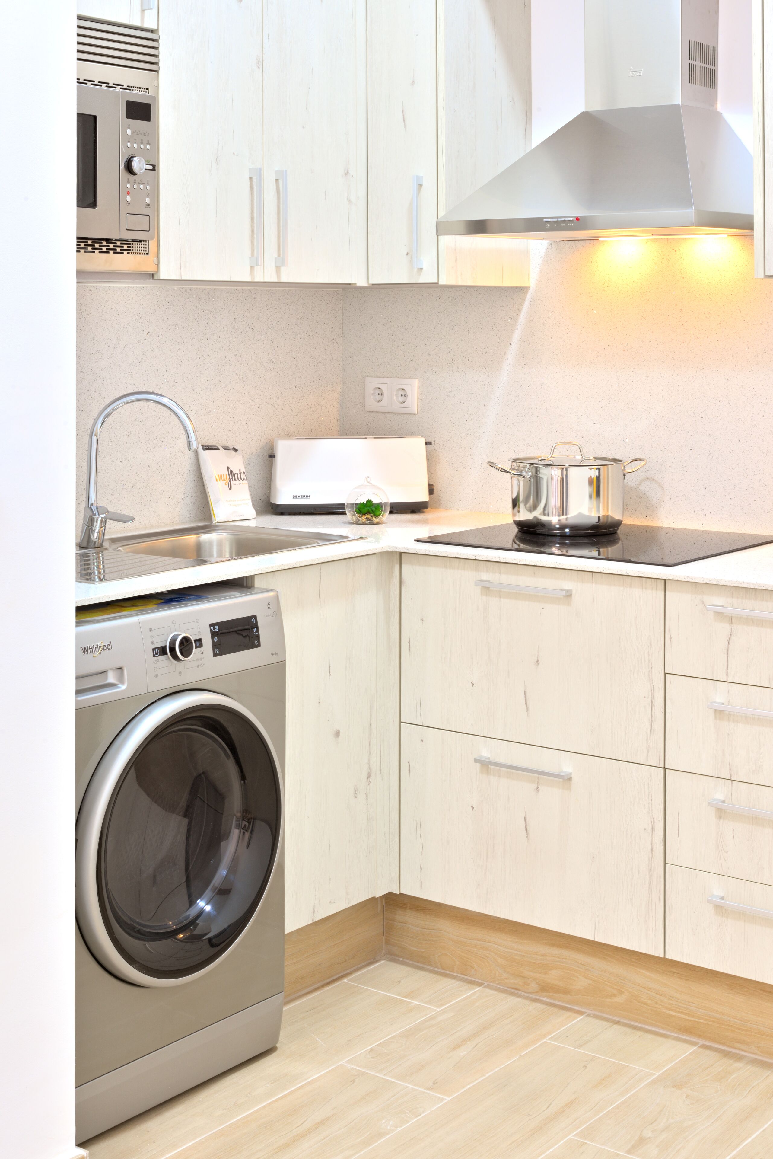 A compact kitchen with a built-in washer, a microwave, and a stove.