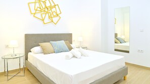 Un lit bien fait, avec des oreillers, une table de chevet avec une lampe et une décoration géométrique fixée au mur.