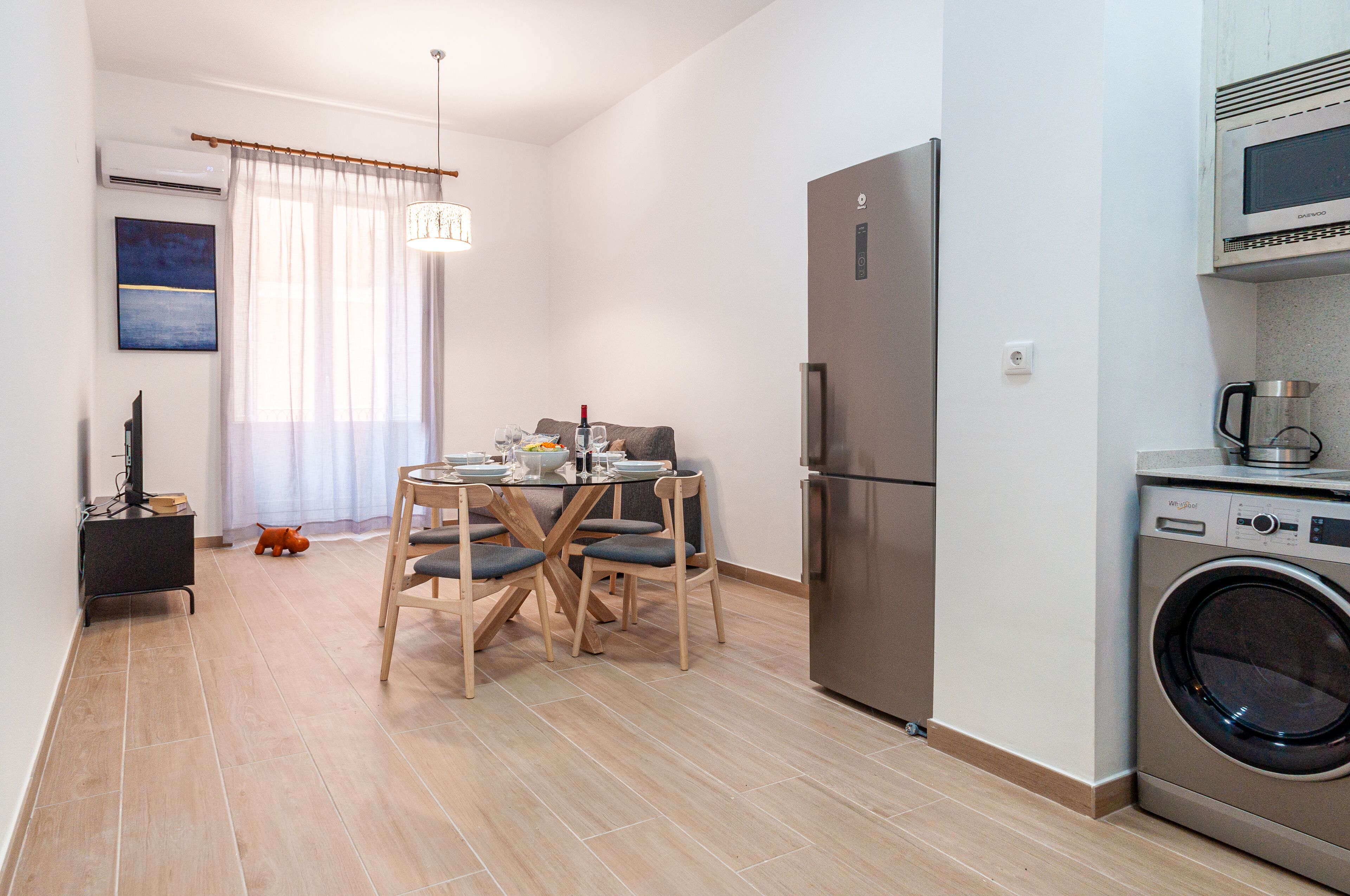 Eine moderne Küche mit einem Edelstahlkühlschrank, einer eingebauten Mikrowelle und einer Frontlader-Waschmaschine.