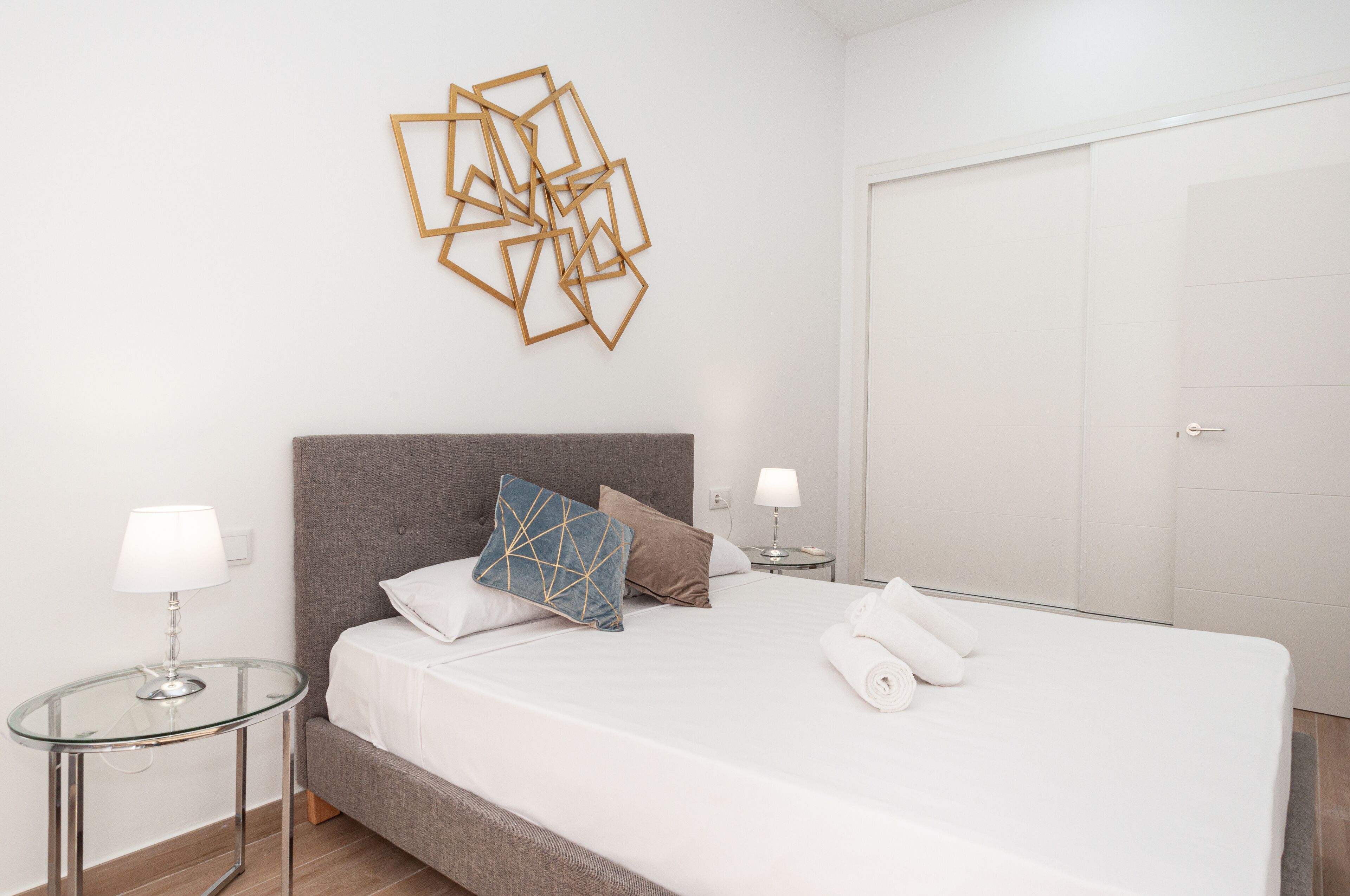 Ein modernes Hotelzimmer mit einem großen Bett, zwei Nachttischen, einem Wandbild und einer weißen Tür.