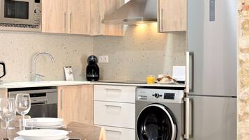 A modern kitchen with wooden cabinets, a stainless steel refrigerator, a built-in washing machine, and a microwave.
