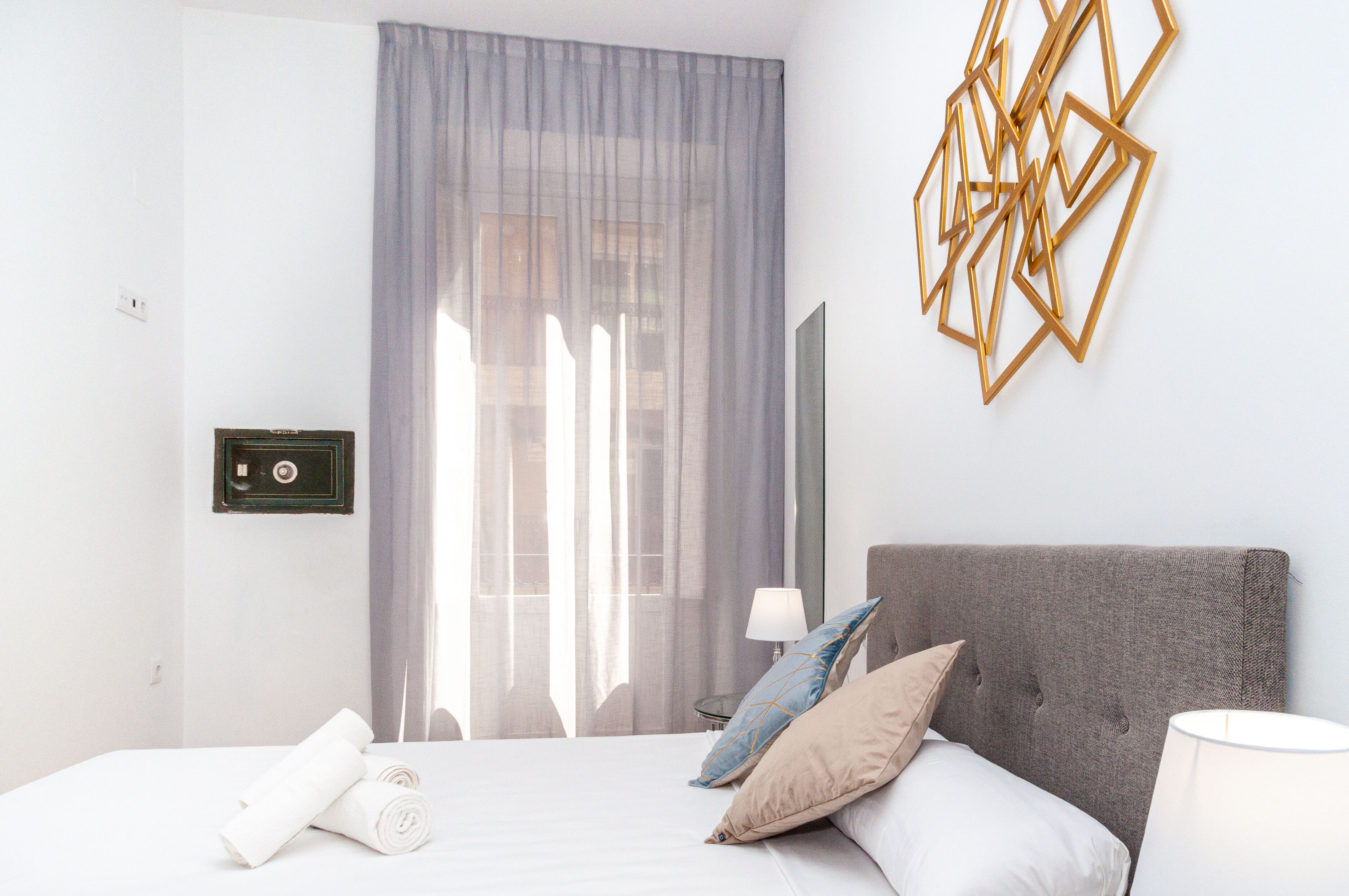 Ein Hotelzimmer mit Bett, Fernseher, Lampe und einem Fenster mit Vorhängen.