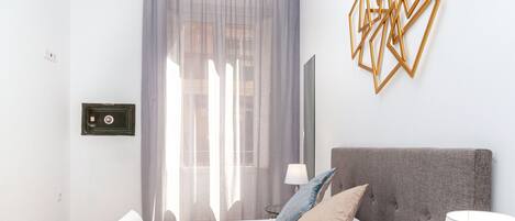 Ein Hotelzimmer mit Bett, Fernseher, Lampe und einem Fenster mit Vorhängen.