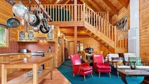A spacious wooden cabin with a dining area, red chairs, a wooden table, and a staircase leading to an upper level. - Stunning holiday home that has you feeling like you are in a Swiss chalet (Blairgowrie)