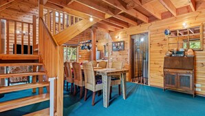 A wooden cabin interior with a dining area, a kitchen, and a staircase. - Stunning holiday home that has you feeling like you are in a Swiss chalet (Blairgowrie)