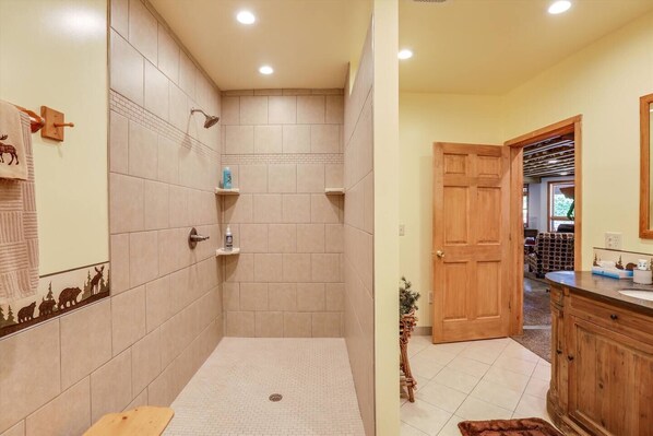 A bathroom with a shower, tiled walls, a wooden door, and a sink area with a mirror. - Lakefront, golf course - "The San Angelo Lodge" (Kimball)