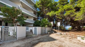 A gated entrance to a building with a white facade, multiple balconies, and surrounding trees. - 2517 Villetta Lido La Pineta by Barbarhouse (Gallipoli)