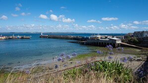 A coastal view with a pier, boats, and a lighthouse.