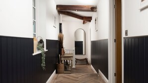 A hallway with dark wooden paneling, a herringbone floor, a wooden bench, and a mirror on the wall.