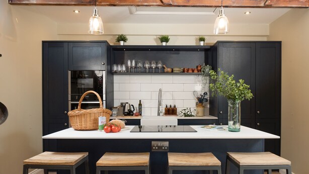 A kitchen with a central island, dark cabinetry, and pendant lighting.