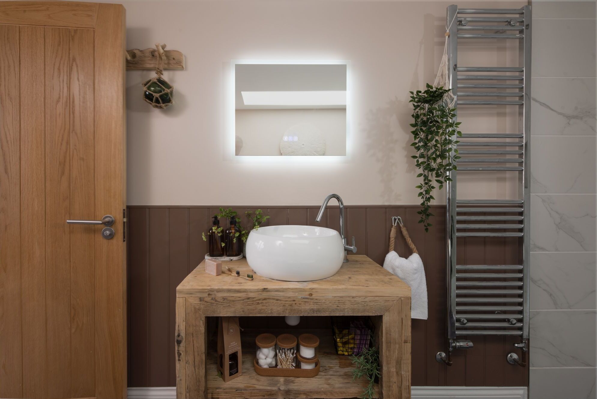 A bathroom with a wooden vanity, a white sink, a mirror, and a towel rack.