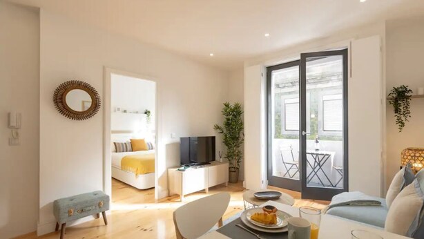 A modern living room with a dining area, a sofa, a television, and a balcony with outdoor seating. - Sweet Flat 4Two in City Center w/ Balcony & Air Conditioning (Porto)