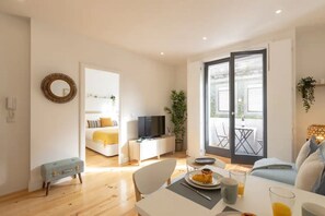 Un soggiorno moderno con zona pranzo, divano, televisione e balcone con posti a sedere esterni.