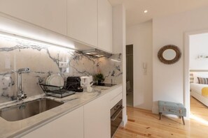 Kitchen features a sink, stainless steel faucet, and a coffee maker on a white countertop.
