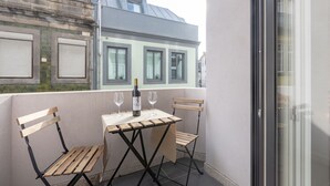 A small balcony with a table and two chairs, a bottle of wine, and two wine glasses. - Sweet Flat 4Two in City Center w/ Balcony & Air Conditioning (Porto)