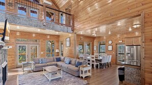 A spacious wooden cabin with a living area, dining space, and a kitchen. - Smokey Treats 5 Bedroom Cabin by RedAwning (Gatlinburg)