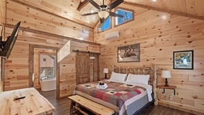 A wooden cabin bedroom with a bed, bench, ceiling fan, and framed pictures on the walls. - Smokey Treats 5 Bedroom Cabin by RedAwning (Gatlinburg)