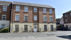 A multi-story brick building with a flat roof, a white door, and multiple windows. - Central Taunton 2-bedroom apartment, great views! (Taunton)
