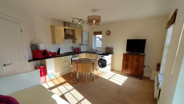 A compact kitchen with a dining area, a washing machine, and a TV. - Central Taunton 2-bedroom apartment, great views! (Taunton)