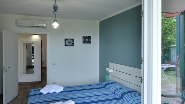Een slaapkamer met een bed, een plafondventilator en uitzicht op de omgeving.