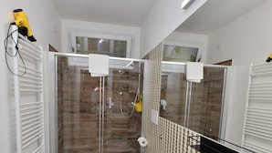 Een moderne badkamer met een douchecabine van glas, een wit toilet en een grote wastafel.