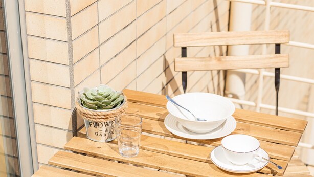 A wooden table with a potted plant, a glass, and white dishes. - Modern 2BR Apart w/ AC and Parking in City Center (Porto)