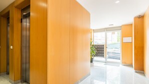 A modern hotel lobby with wooden paneling, a glass door entrance, and a tiled floor. - Modern 2BR Apart w/ AC and Parking in City Center (Porto)