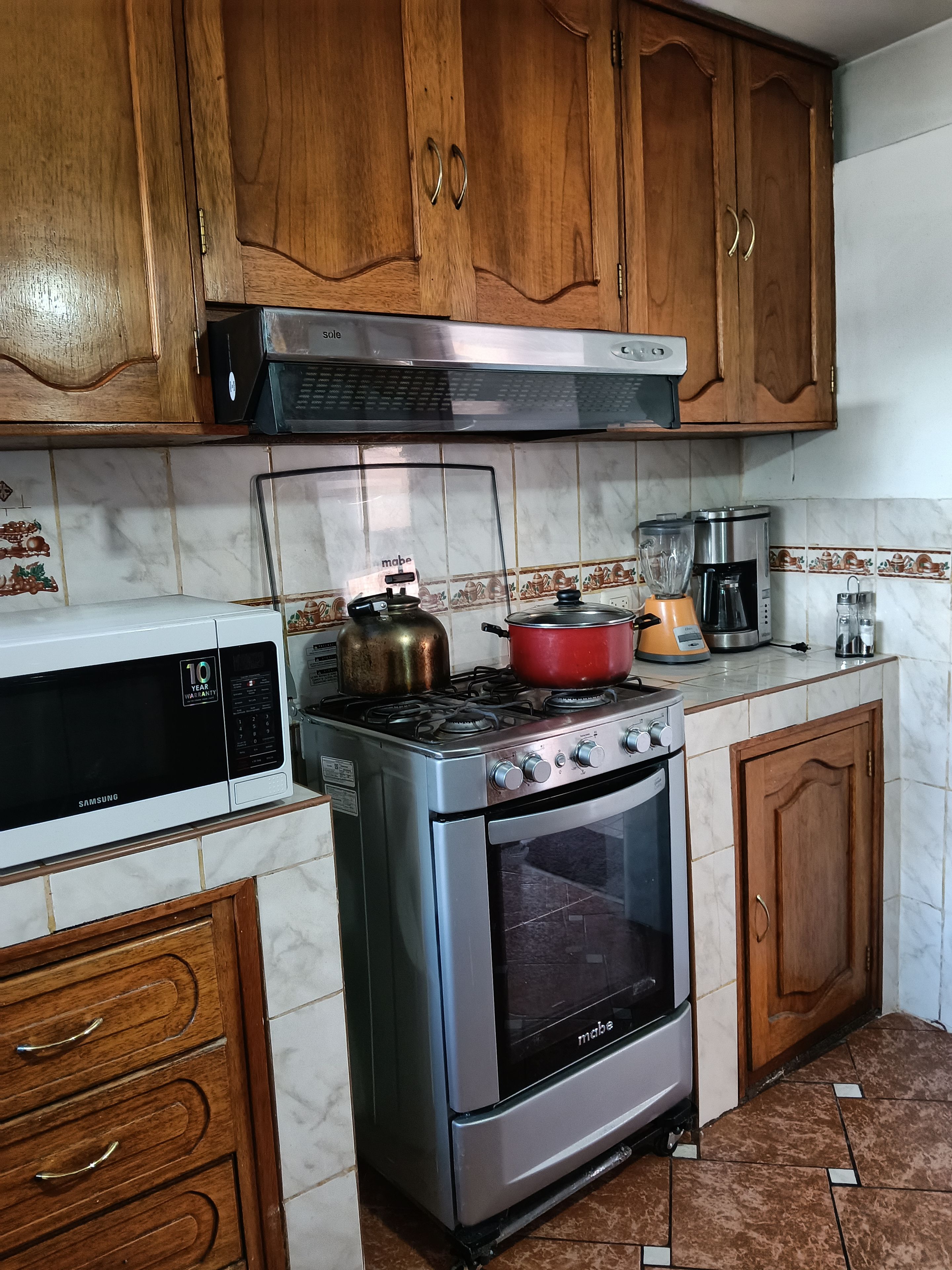 Una cocina con armarios de madera, una estufa de acero inoxidable, un microondas y una cafetera.