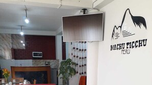 Un saló modern amb un sofà vermell, una taula de cafè negra amb un disseny floral i un televisor fixat a la paret.