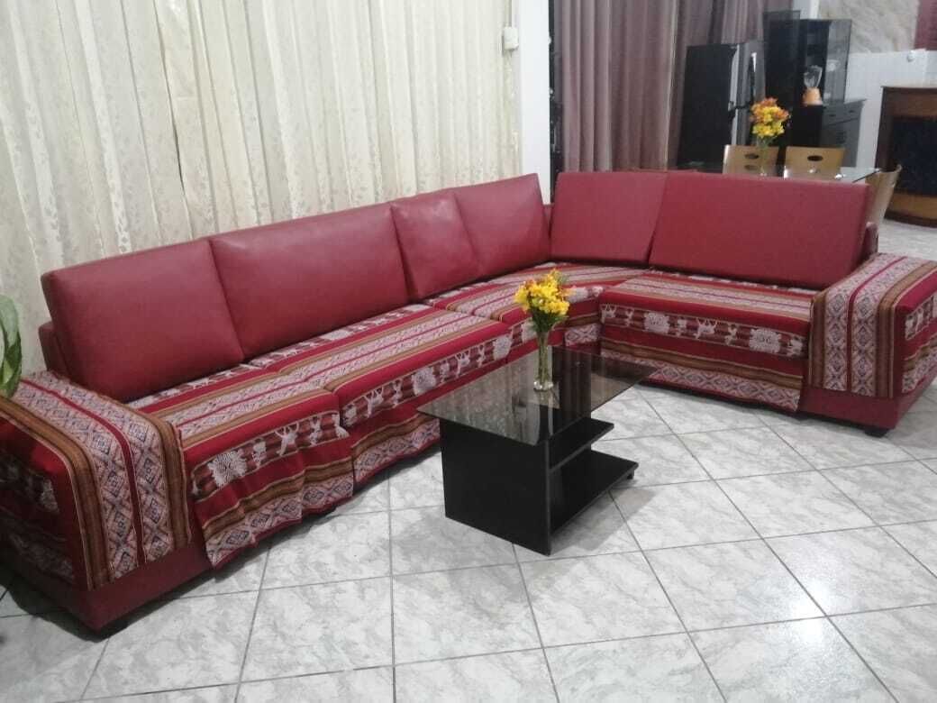 A red sectional sofa with patterned throw pillows and a black coffee table with a vase of yellow flowers.