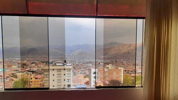 Una habitació amb un finestral gran que dona a una vista de la ciutat amb muntanyes al fons.
