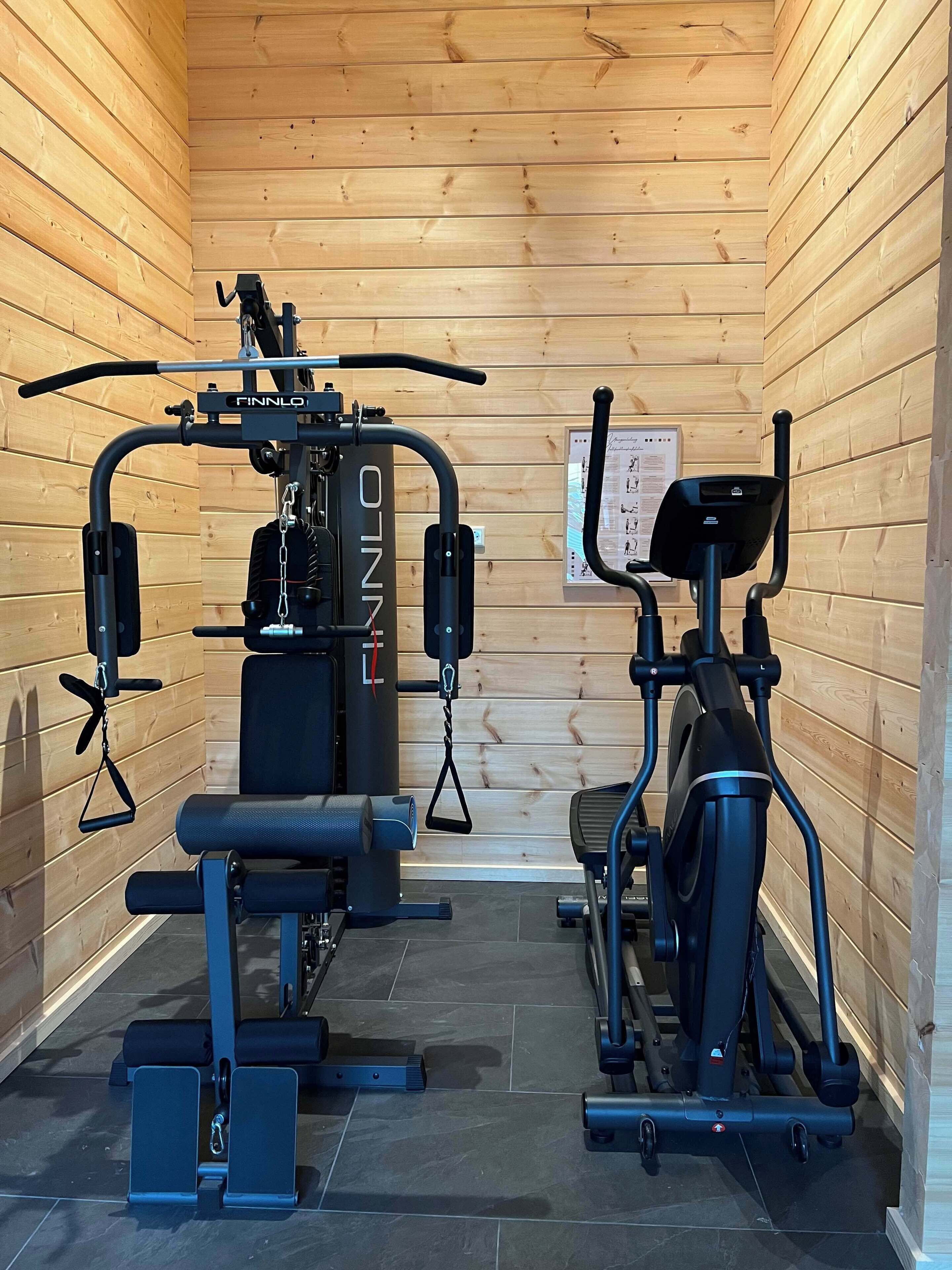 A gym with various exercise equipment, including a bench press, a squat rack, and a treadmill.