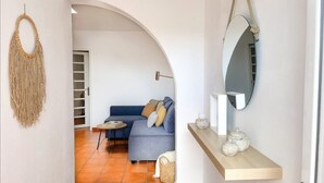 Una sala de estar moderna con un sofá azul, una mesita redonda y un espejo en la pared.