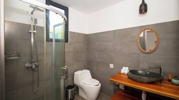 A modern bathroom with a glass-enclosed shower, a white toilet, and a wooden vanity with a round mirror.