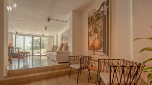A modern living room with a sofa, chairs, and a dining area.