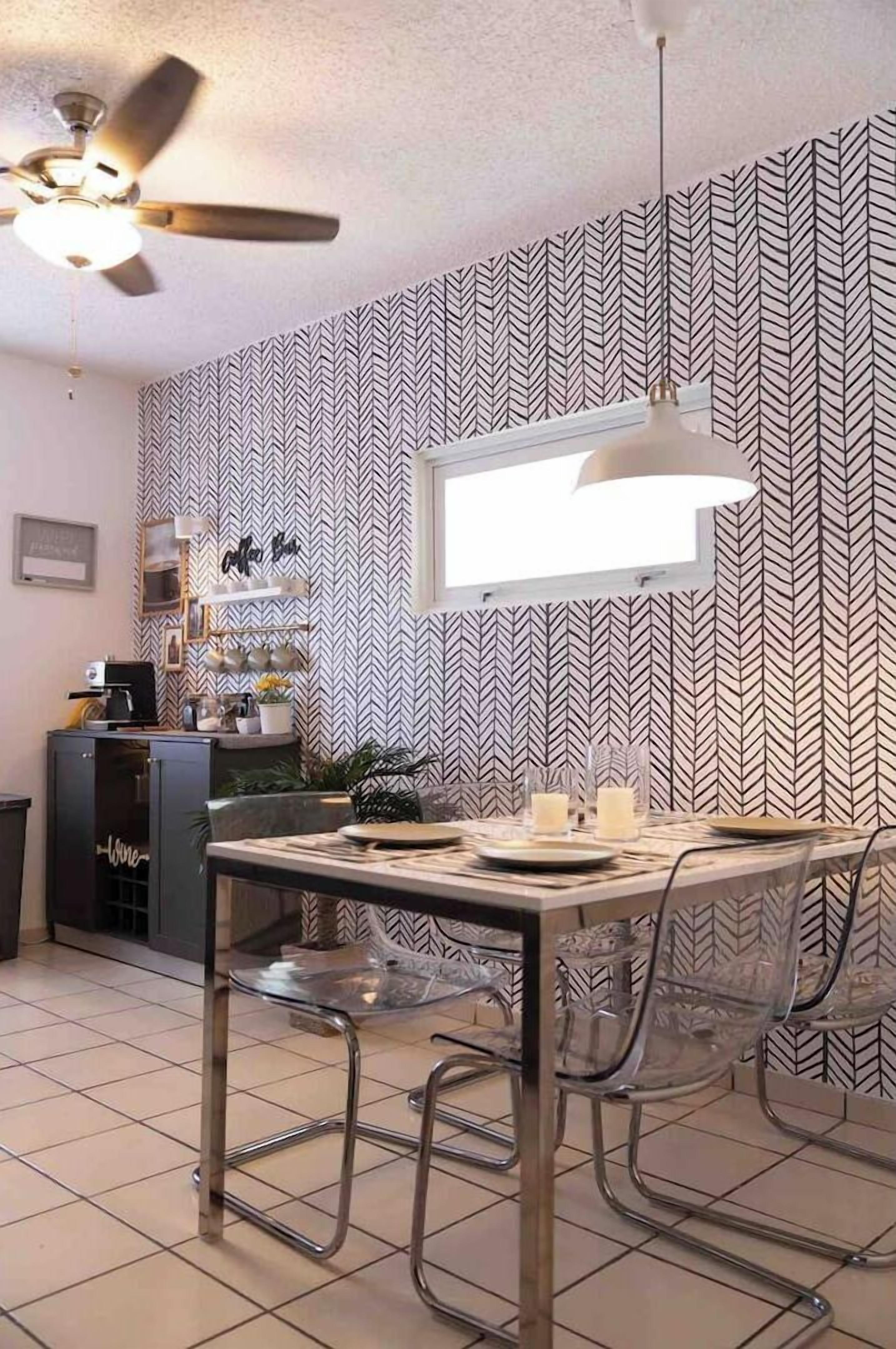 A dining area with a modern table and chairs, a ceiling fan, and a patterned wallpaper.