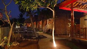 A well-lit outdoor area with a pathway leading to a building with a thatched roof. - Honeybee Hut Lembongan (Lembongan Island)