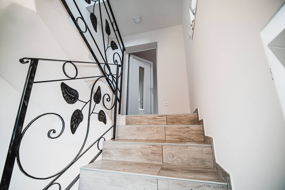 A staircase with a metal railing featuring leaf designs, leading to a door.