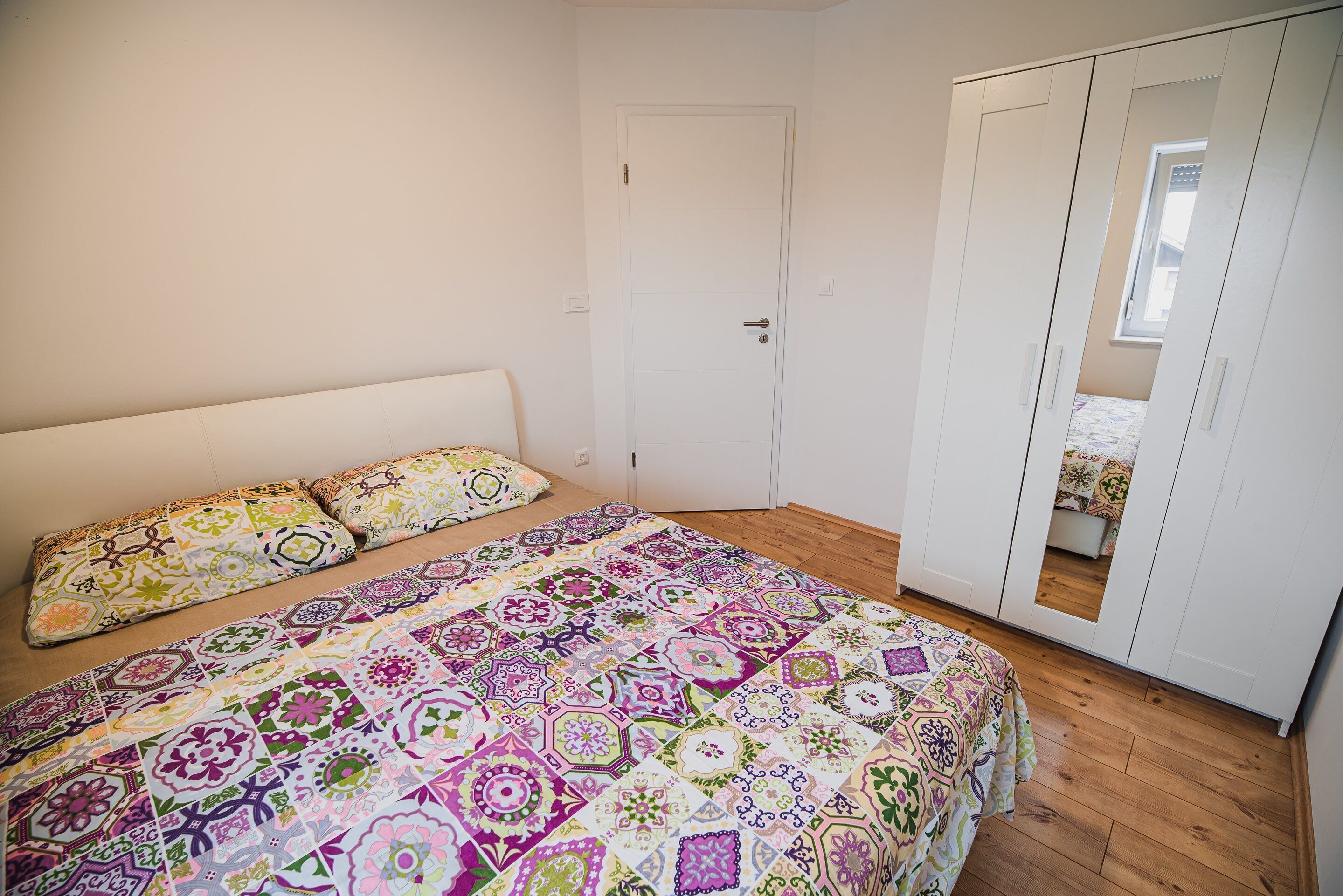 Ein Schlafzimmer mit einem Bett, einem Kleiderschrank und einer Tür.