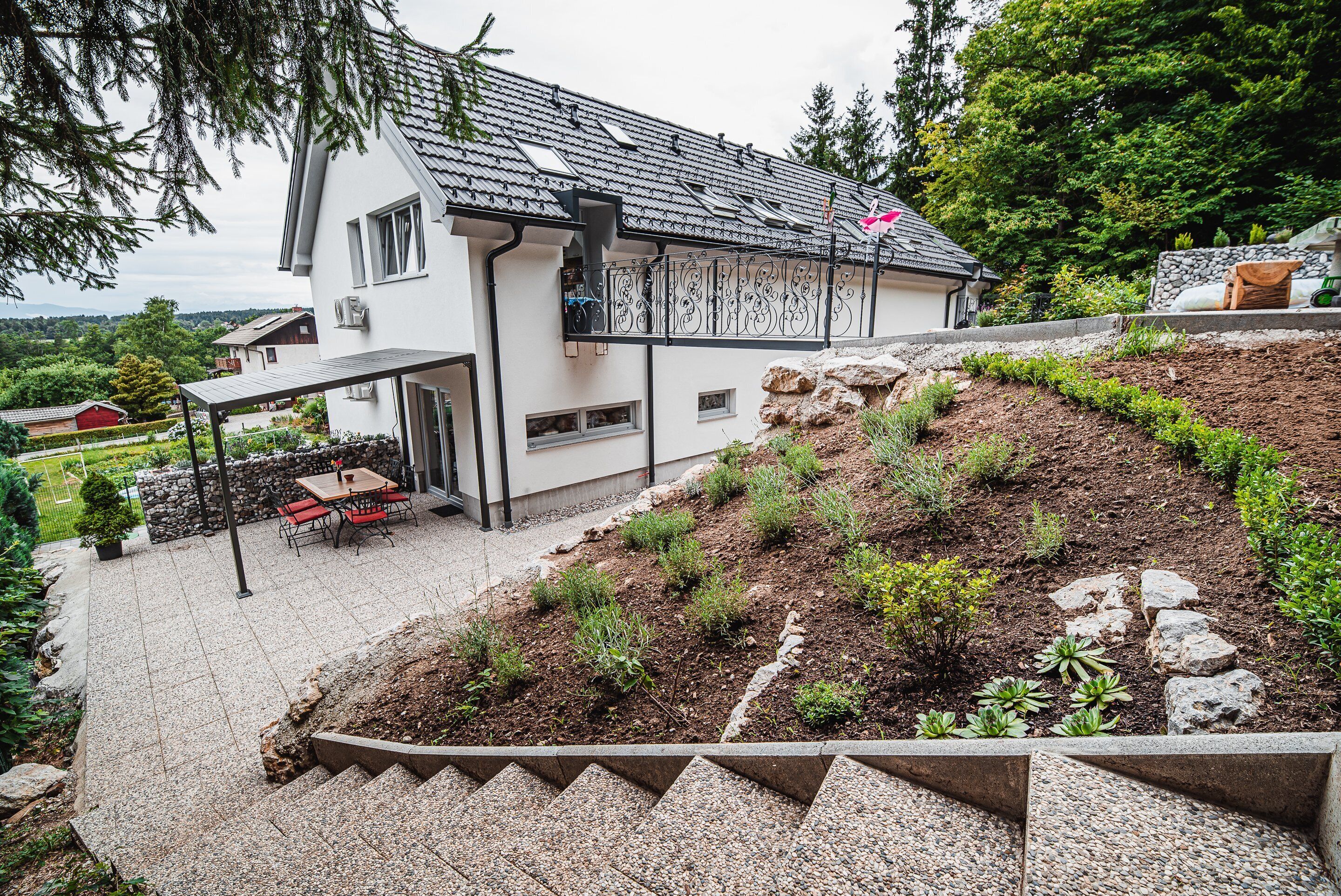 A house with a patio, outdoor seating, and a landscaped garden.