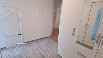 A room with a wardrobe, a radiator, and a hanging clothes rack.