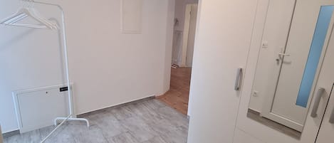 A room with a wardrobe, a radiator, and a hanging clothes rack.