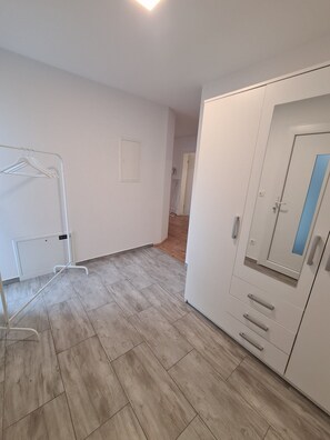 A room with a wardrobe, a radiator, and a hanging clothes rack.