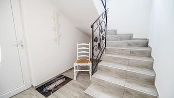A staircase with a white chair and a doormat at the bottom.