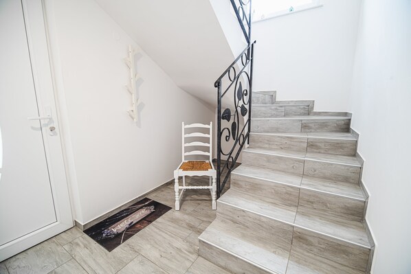 A staircase with a white chair and a doormat at the bottom.