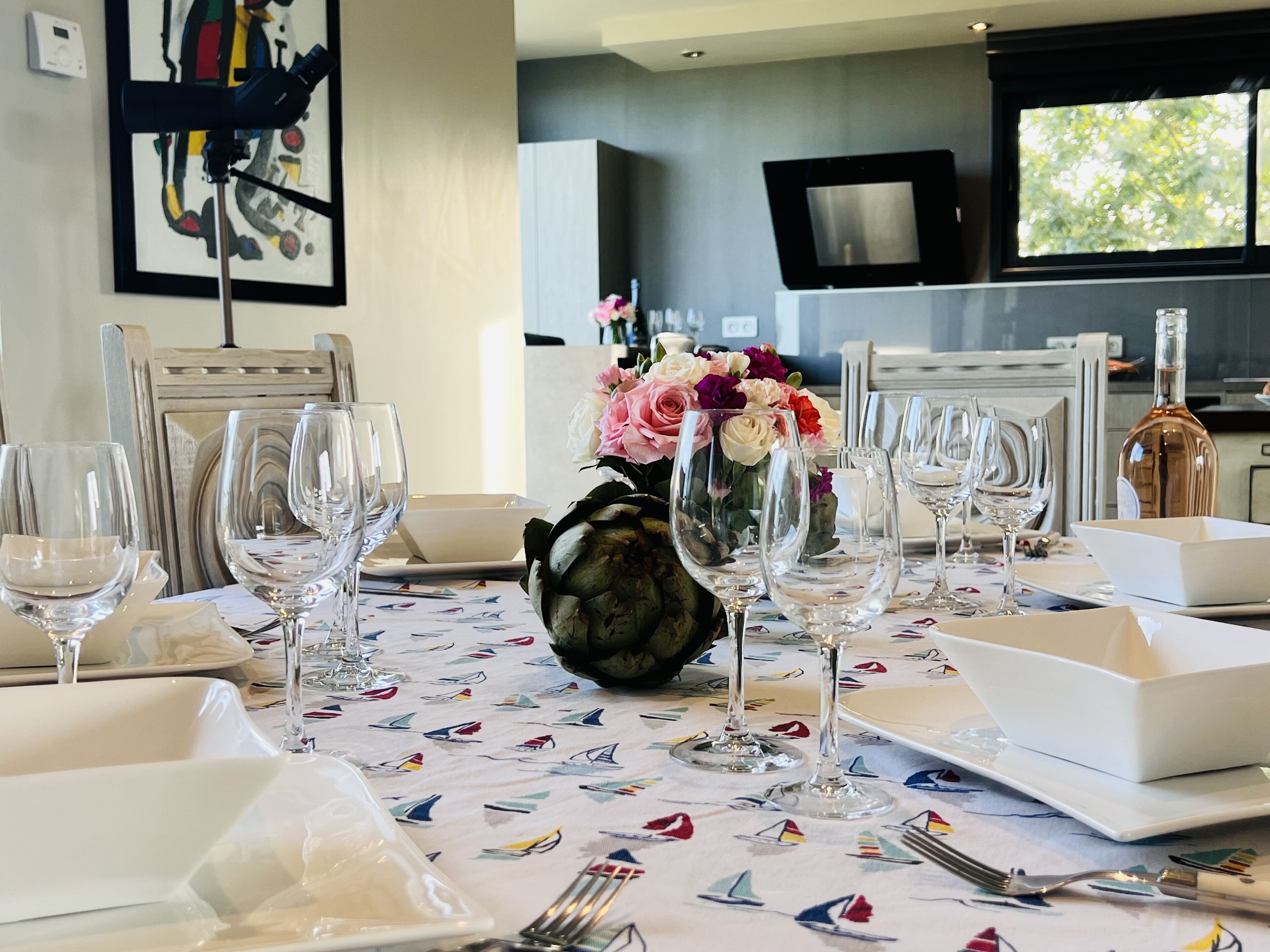 A dining table set with wine glasses, plates, and a vase of flowers.