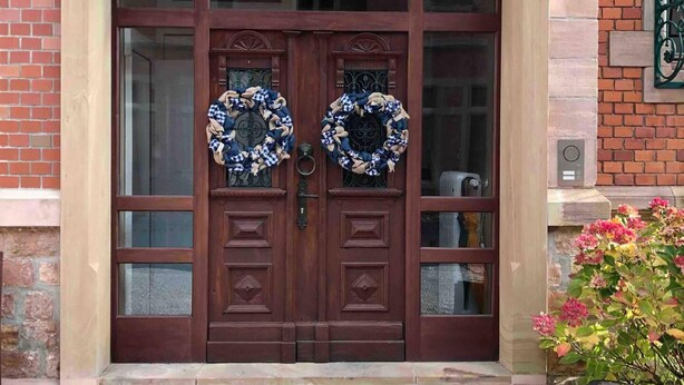 Une porte en bois à deux battants, ornée de panneaux de verre et de deux guirlandes suspendues à la porte.